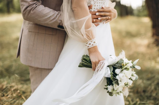 Scène de mariage en extérieur avec couple enlacé dans un jardin verdoyant